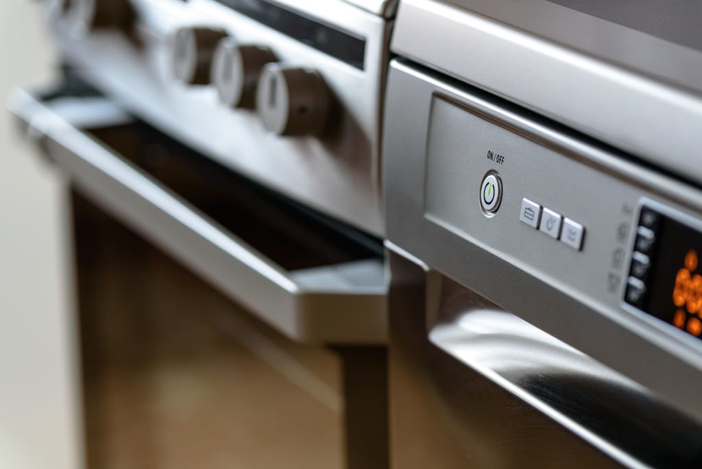 Photo by AS Photography Close-up view of modern stainless steel kitchen appliances with focus on dishwasher and oven.